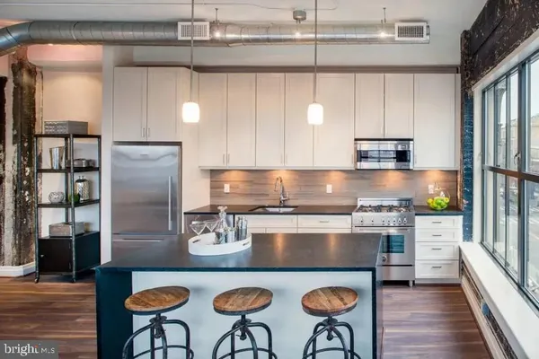 a kitchen with stainless steel appliances granite countertop a stove a refrigerator a sink a dining table and chairs with wooden floor