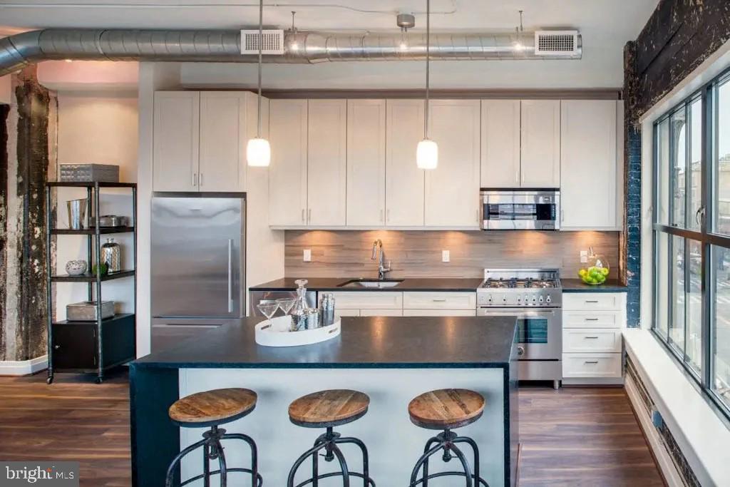 1350 R Street Northwest, Unit 1 BR 1 Washington, DC 20009 - Photo 4 of 5 a kitchen with stainless steel appliances granite countertop a stove a refrigerator a sink a dining table and chairs with wooden floor