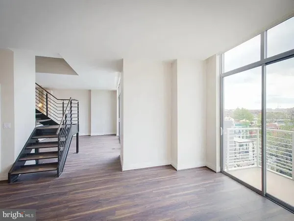 a view of an empty room with wooden floor and stairs