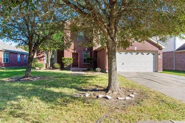 a tree in front of a brick house with a large tree