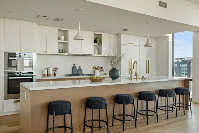 a kitchen with stainless steel appliances granite countertop white cabinets and chairs