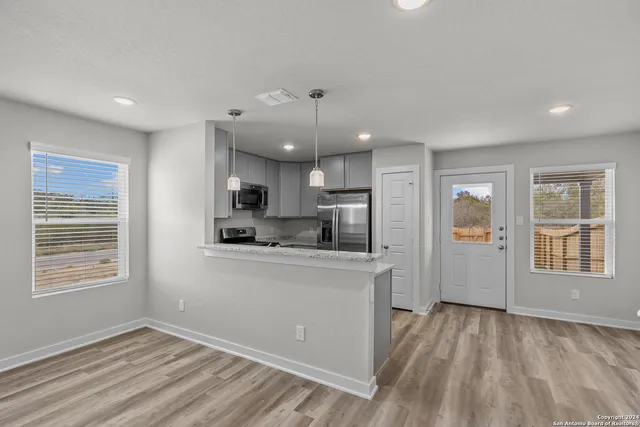 a kitchen with stainless steel appliances granite countertop a refrigerator a sink dishwasher a stove and white countertops with wooden floor