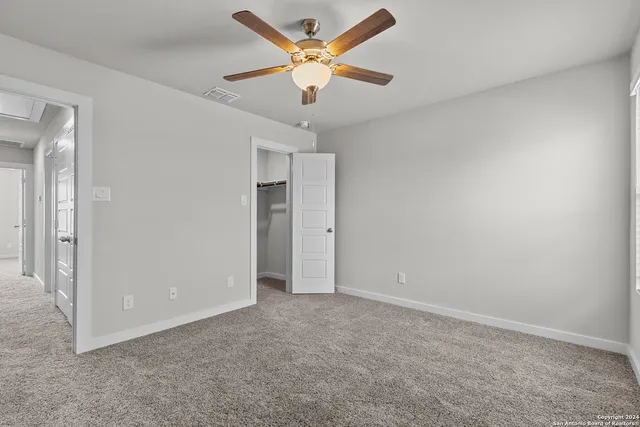 an empty room with closet and a ceiling fan