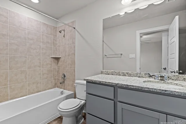 a bathroom with a granite countertop sink a toilet a mirror and bathtub
