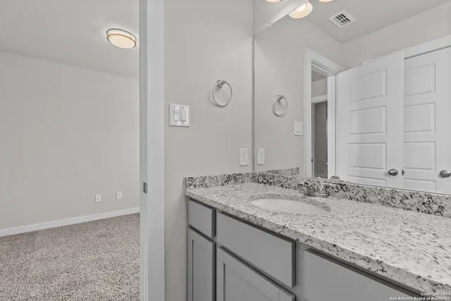 a bathroom with a granite countertop sink and a mirror