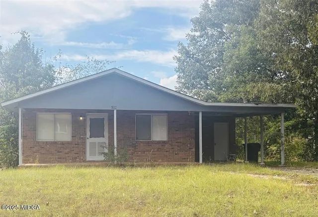 a front view of house with yard and trees in the background