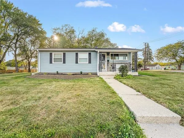 a front view of house with yard and trees in the background