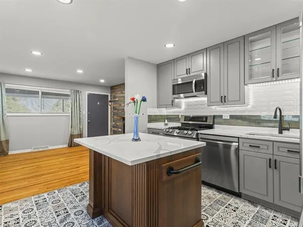 a kitchen with kitchen island a sink stainless steel appliances and cabinets