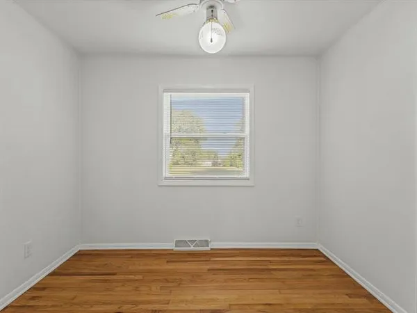 an empty room with wooden floor closet and windows