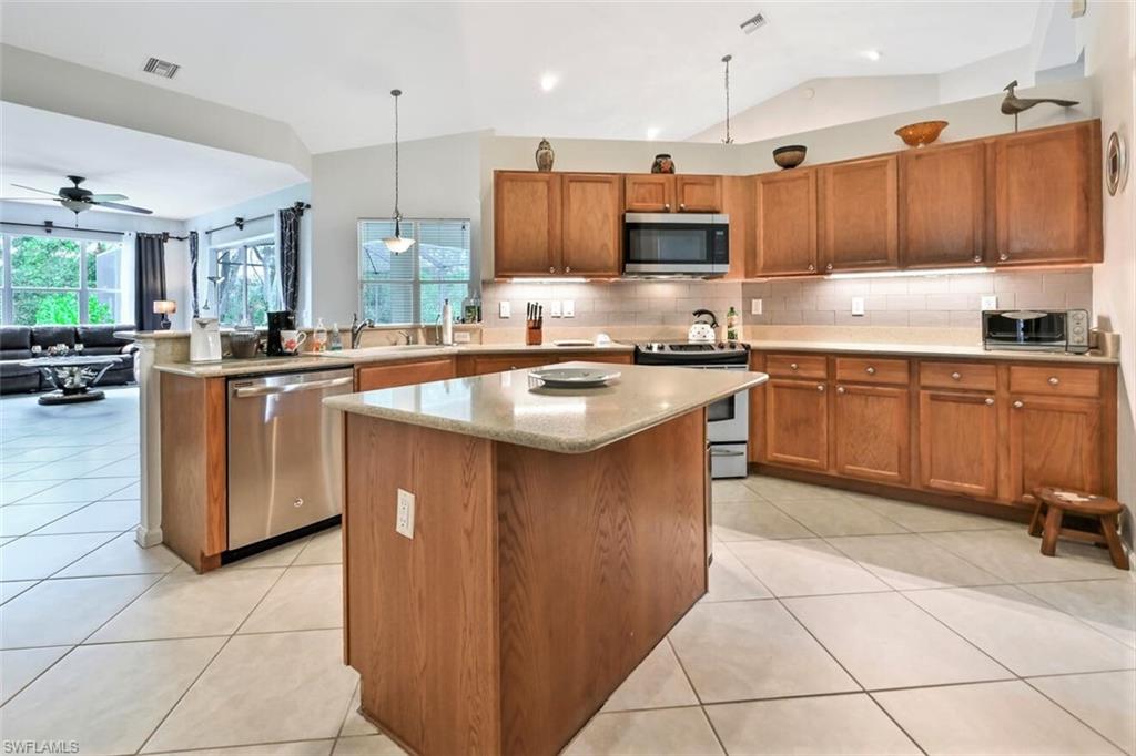 6545 Chestnut Circle Naples, FL 34109 - Photo 11 of 43 a kitchen with stainless steel appliances granite countertop a stove top oven a sink dishwasher and a stove with wooden cabinets