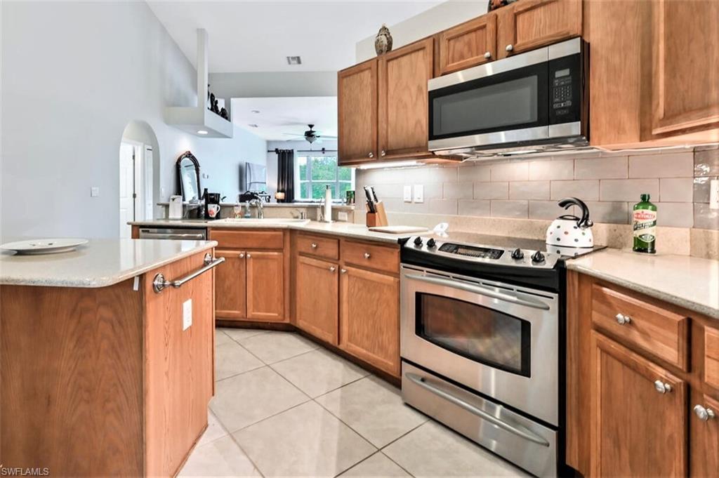 6545 Chestnut Circle Naples, FL 34109 - Photo 12 of 43 a kitchen with stainless steel appliances white cabinets granite counter tops and a stove top oven