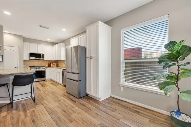 a kitchen with a refrigerator and wooden floor