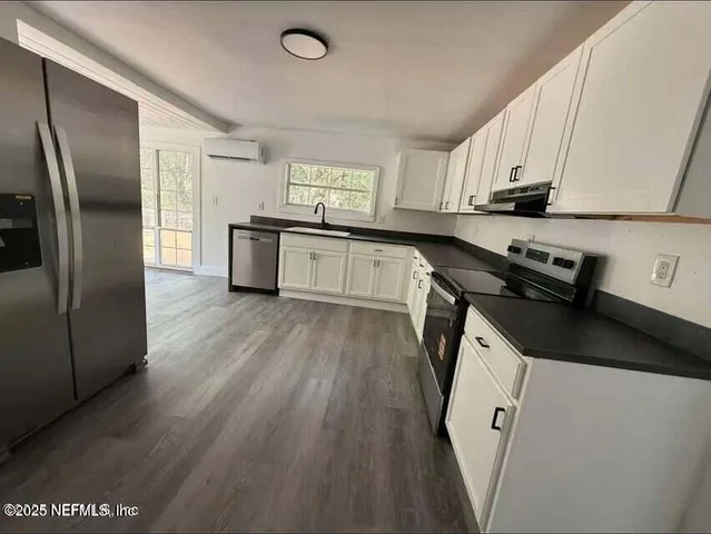 a kitchen with granite countertop a refrigerator a sink a stove and cabinets