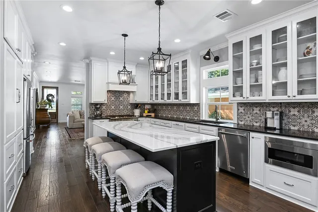 a kitchen with stainless steel appliances granite countertop a stove a sink dishwasher a refrigerator and a dining table with wooden floor