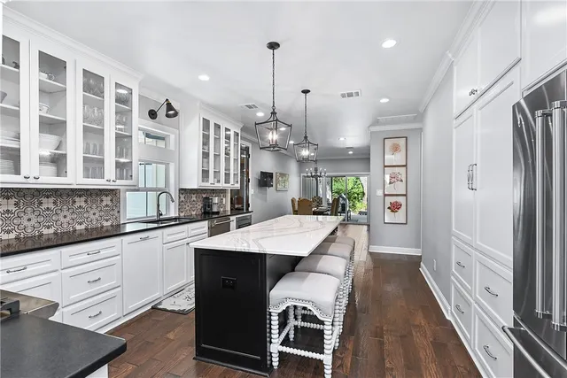 a large kitchen with granite countertop a large island in the center and stainless steel appliances