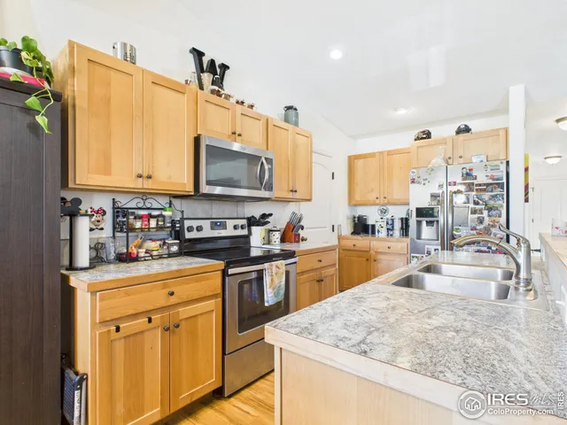 a kitchen with stainless steel appliances granite countertop a sink a stove and a wooden floors