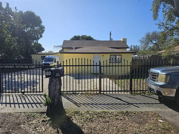a view of a brick house with large trees in front of it