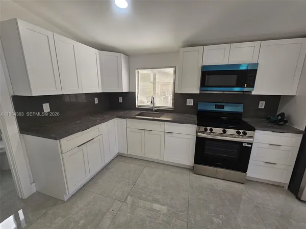 a kitchen with granite countertop a refrigerator stove and sink
