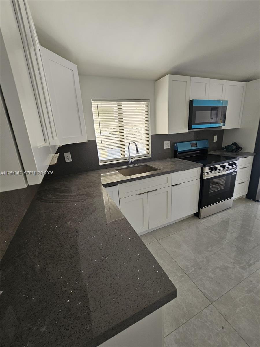 1148 Northwest 100th Street, Unit 1 Miami, FL 33150 - Photo 20 of 32 a kitchen with stainless steel appliances a sink stove and cabinets