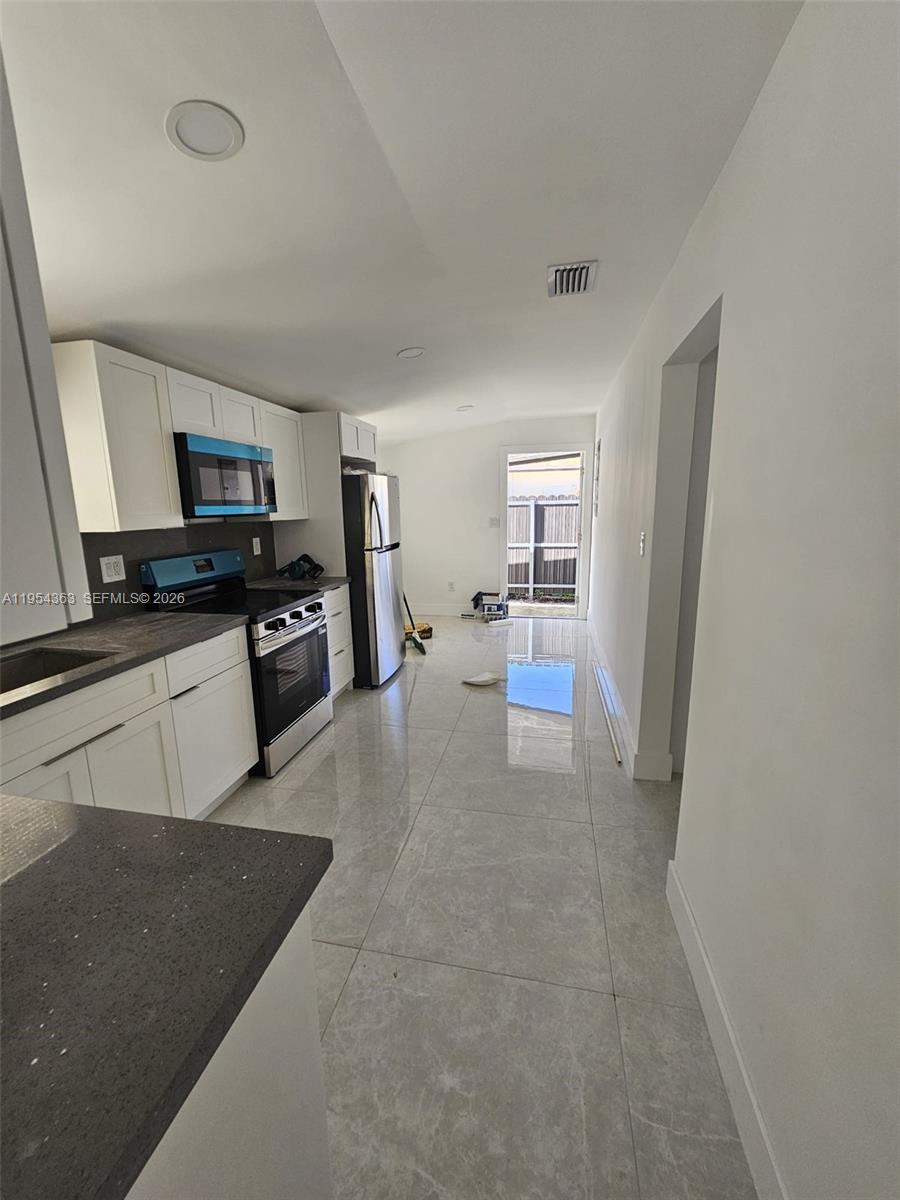 1148 Northwest 100th Street, Unit 1 Miami, FL 33150 - Photo 21 of 32 a kitchen with granite countertop a refrigerator stove and sink