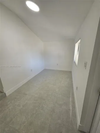 a view of a hallway to an empty room with a kitchen