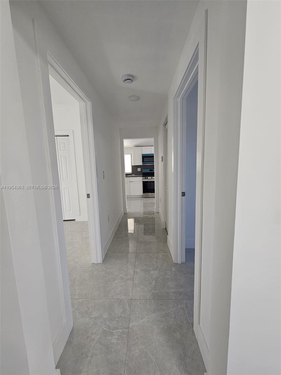 1148 Northwest 100th Street, Unit 1 Miami, FL 33150 - Photo 7 of 32 a view of a hallway to an empty room with a kitchen