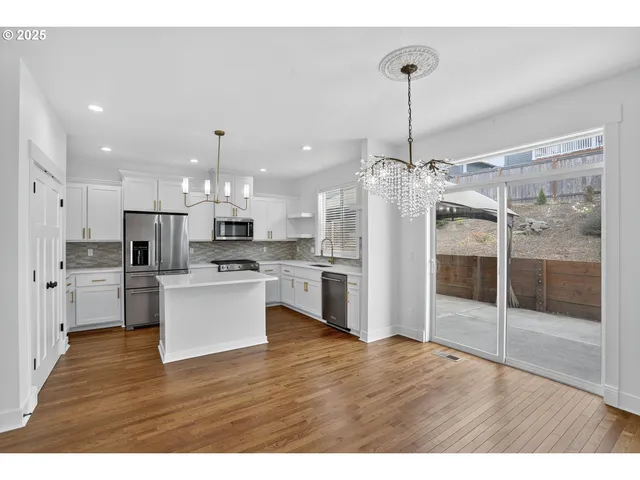 a kitchen with stainless steel appliances kitchen island granite countertop a refrigerator and a view of living room