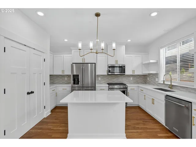 a large kitchen with stainless steel appliances kitchen island granite countertop a stove a sink a refrigerator and a granite counter tops