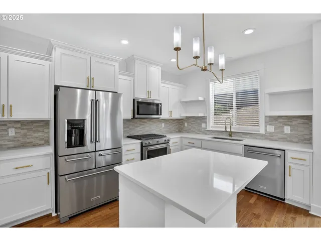 a kitchen with kitchen island a counter space a sink appliances and cabinets