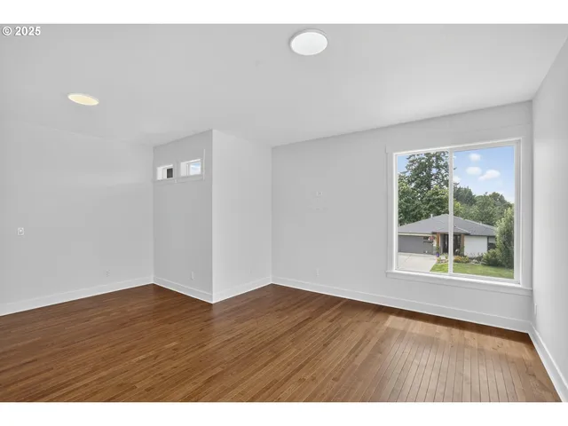 a view of an empty room with a window and wooden floor