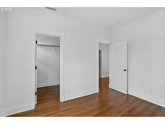 a view of an empty room with wooden floor and closet