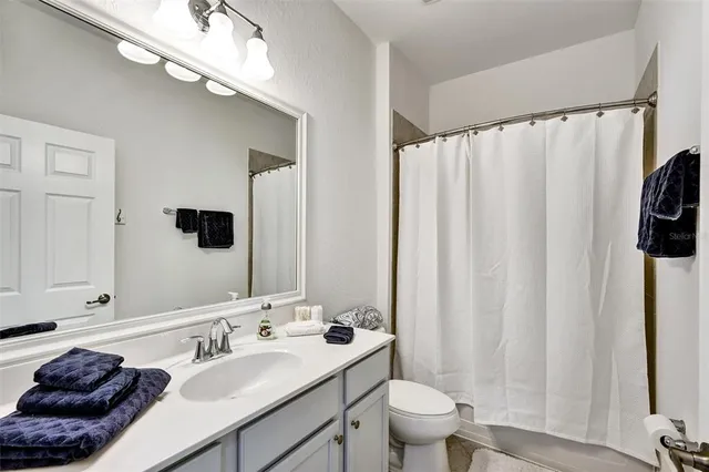 a bathroom with a granite countertop sink a toilet and a mirror