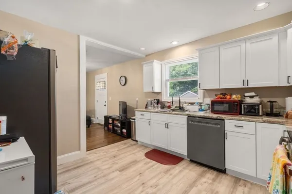 a kitchen with stainless steel appliances granite countertop a refrigerator a sink dishwasher a stove and white countertops with wooden floor