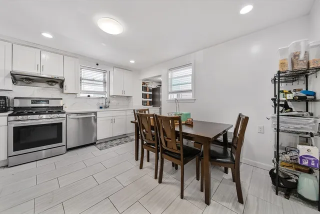 a kitchen with stainless steel appliances a table and chairs in it