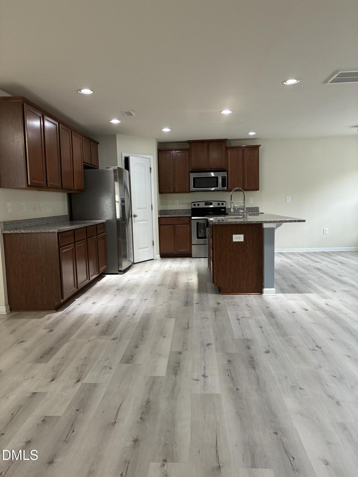 4325 Lyman Avenue Raleigh, NC 27616 - Photo 6 of 52 a large kitchen with stainless steel appliances kitchen island granite countertop a large counter top and wooden floors