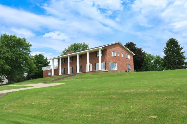 a view of a house with a big yard and large trees