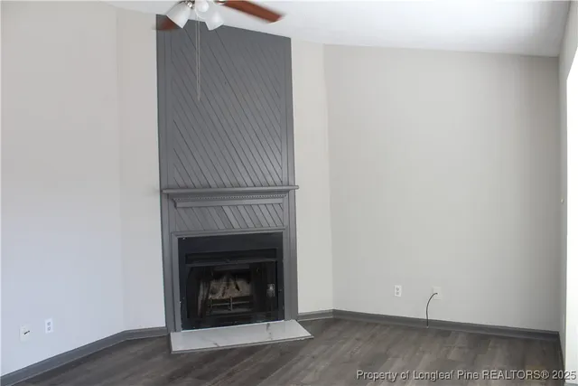 a view of an empty room with wooden floor and a fireplace