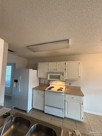 a kitchen with white cabinets and refrigerator