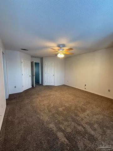 a view of an empty room and chandelier fan