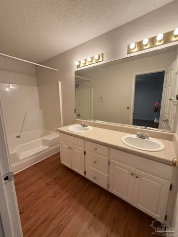a bathroom with a double vanity sink a mirror and a bathtub