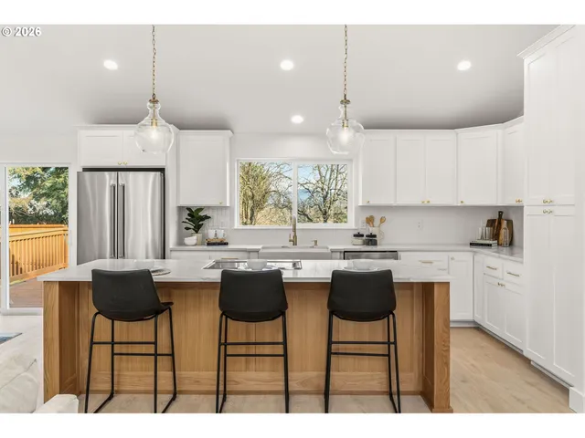 a kitchen with kitchen island granite countertop a sink and white cabinets