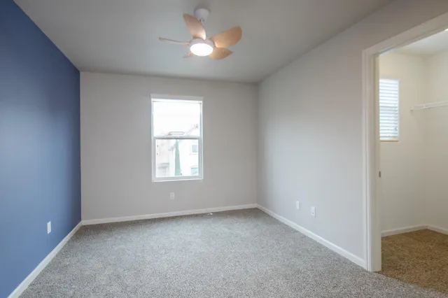 an empty room with a window and chandelier fan