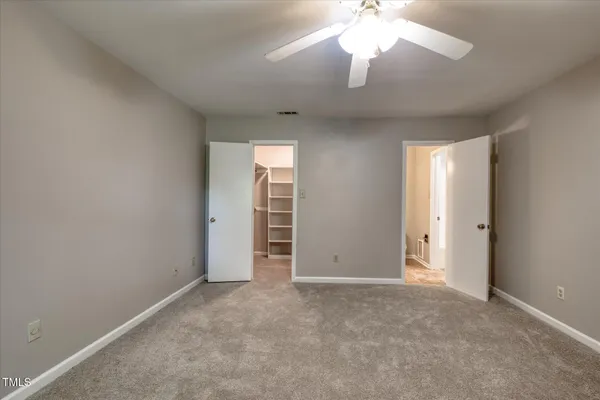an empty room with windows and chandelier fan