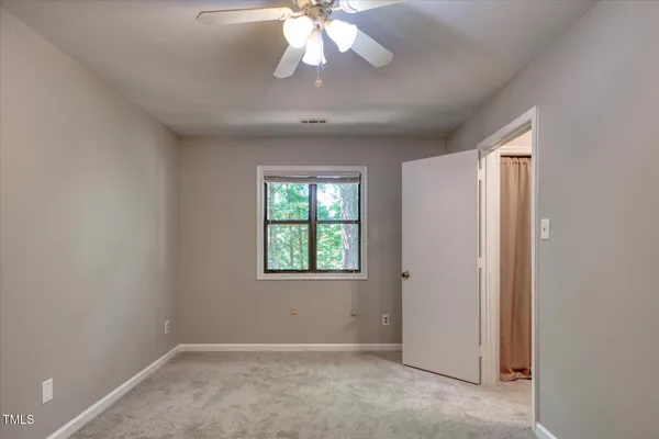 an empty room with windows and fan