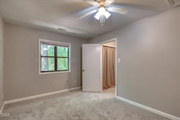 an empty room with chandelier fan and windows