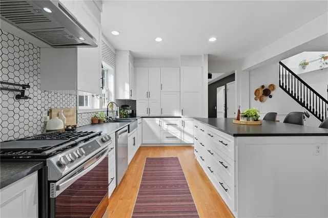 a kitchen with stainless steel appliances granite countertop a stove a sink and white cabinets