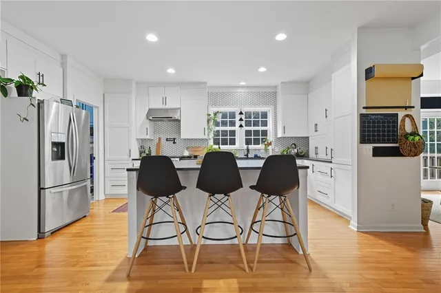 a kitchen with stainless steel appliances granite countertop a refrigerator and a stove top oven with wooden floor
