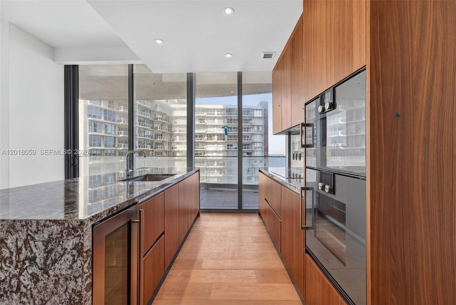 175 Southeast 25th Road, Unit 1004 Miami, FL 33129 - Photo 16 of 40 a large kitchen with kitchen island a large window a sink and stainless steel appliances