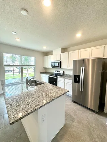 a kitchen with granite countertop a refrigerator and a sink