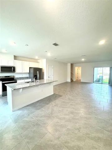 a large kitchen with kitchen island a sink a stove and a refrigerator